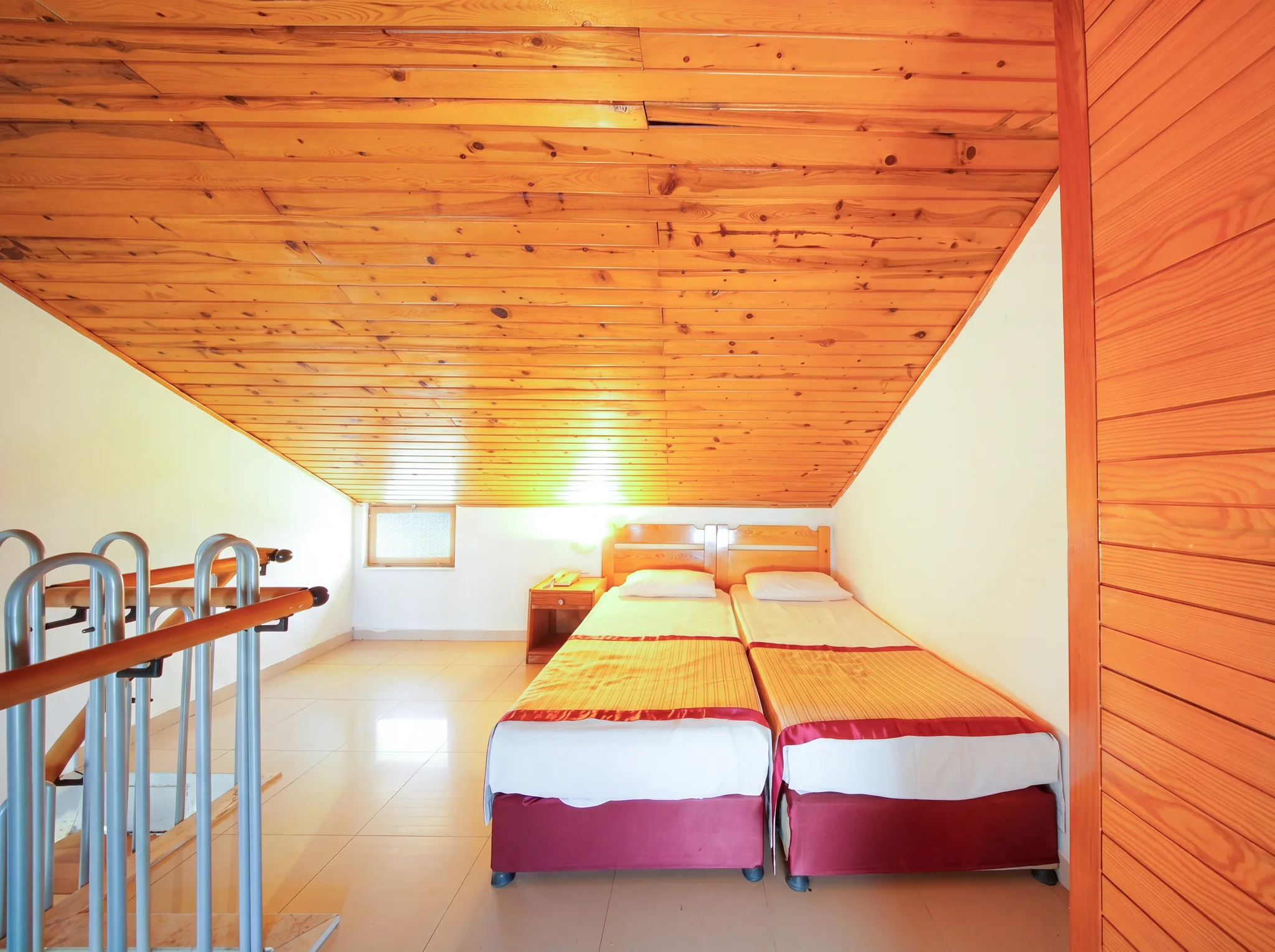 Zwei Betten unter der Holzdecke im Obergeschoss des Familienzimmers