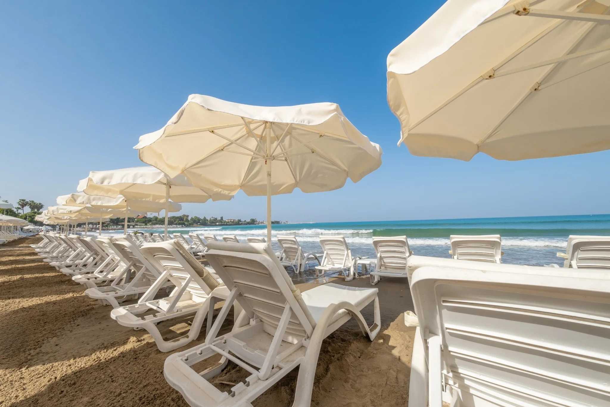 Weiße Sonnenschirme und Liegen am Tropic-Strand