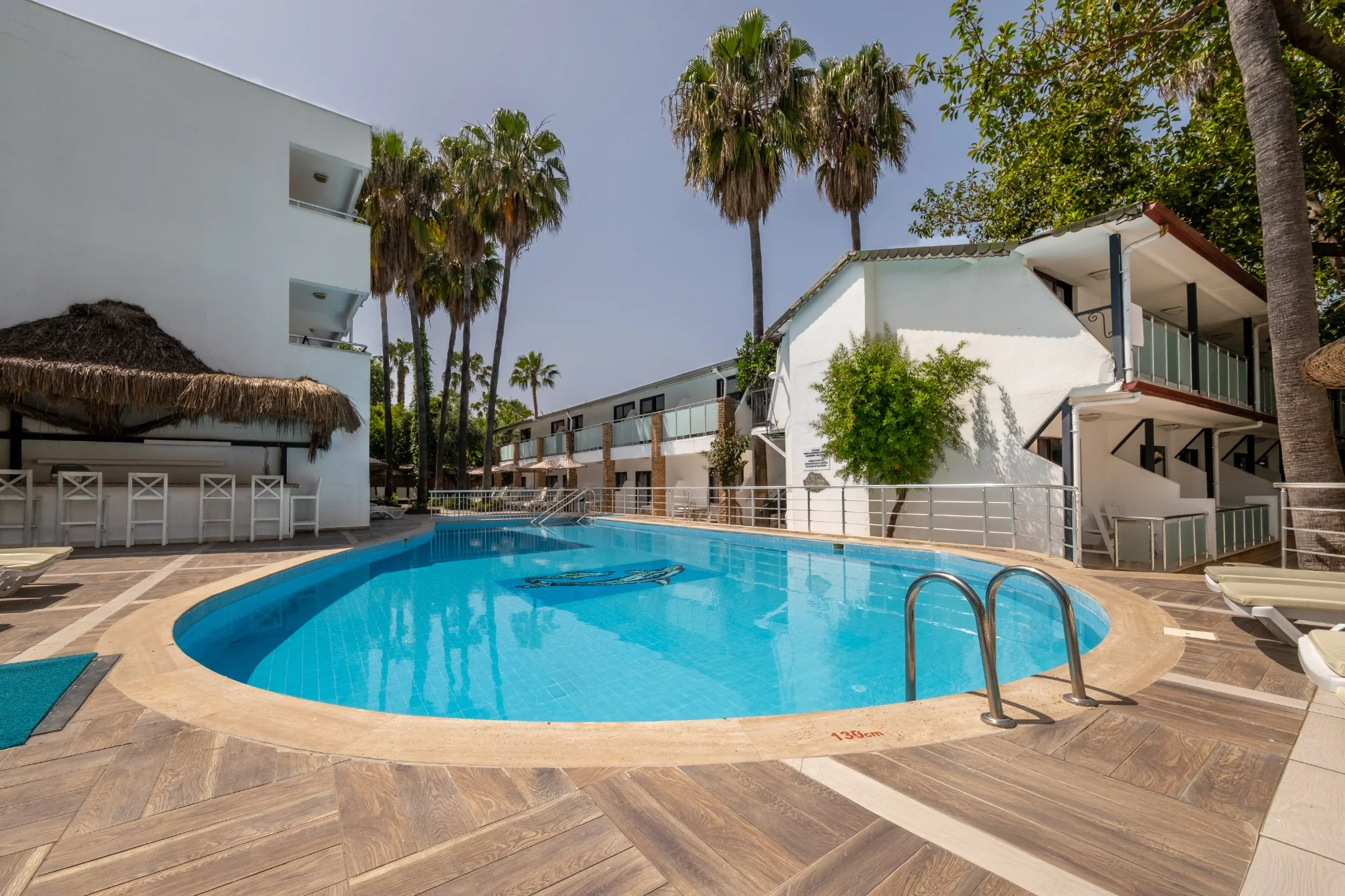 Der Pool zwischen Palmen und weißen Gebäuden